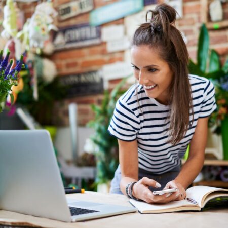 Woman leaning on counter looking at laptop